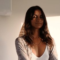 Alexandra is standing her eyes closed as she engages in a reiki healing session.