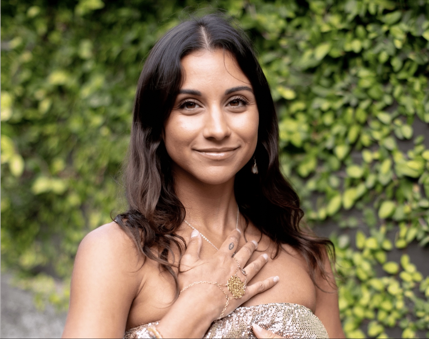Alexandra is looking straight ahead with her right hand on her heart. There is a hand chain on her right hand. She is preparing for a reiki energy work session.