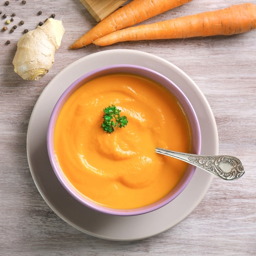 An overhead view of a bowl of carrot soup with parsley garnish created by Certified Nutritional Therapy Practitioner, Julia Stephens.