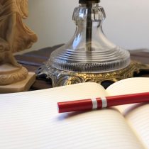 The book Dynamic Counseling and Coaching rests on an open, lined notebook beside a decorative glass lamp and a beige statue on a wooden surface.