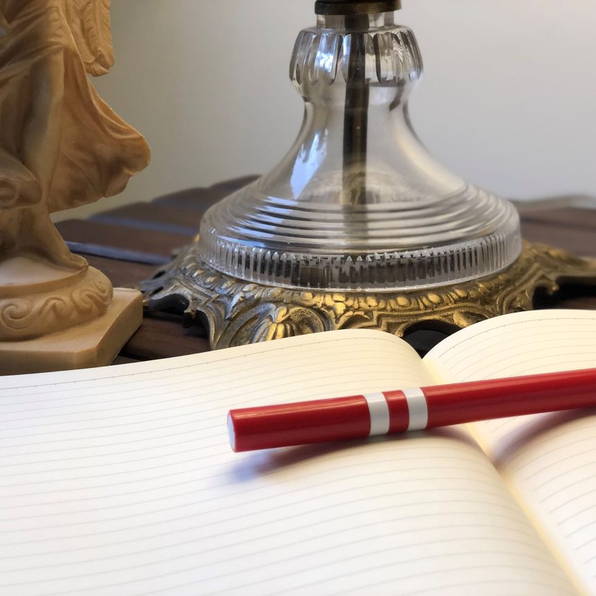 The book Dynamic Counseling and Coaching rests on an open, lined notebook beside a decorative glass lamp and a beige statue on a wooden surface.