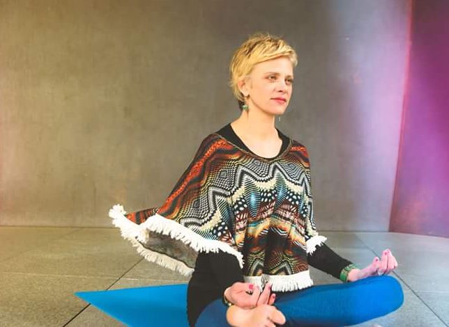 Gabby, a Pranayama breathing techniques instructor, is sitting in a meditation position.