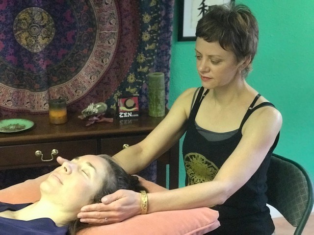 Gabby, an expert reiki practitioner, has her hands on either side of a client. Gabby also offers online reiki healing sessions.