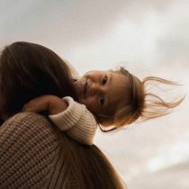 A person with long dark hair is holding a young child over their shoulder. This image represents the Parenting with Purpose online course.
