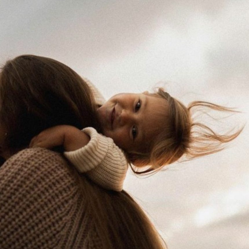 A person with long dark hair is holding a young child over their shoulder. This image represents the Parenting with Purpose online course.