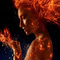 A woman with fiery hair and glowing cracks on her skin holds flames in her hand against a dark background, creating a powerful and mystical effect.