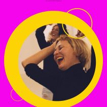 A woman in a black turtleneck laughs joyfully with her hands in her hair, reflected in a mirror. Bright pink and yellow circles frame the image, promoting Laughter As A Tool—a fun team wellness activity with FALL IN LAUGH at the top.