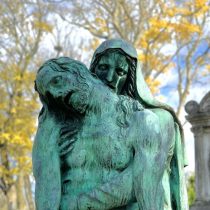 A Grief Support Session is symbolized by a bronze statue showing a sorrowful figure cradling a lifeless body, outdoors among blurred autumn trees with yellow leaves in the background.
