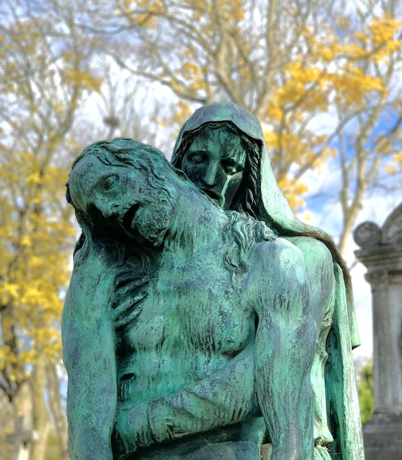 A Grief Support Session is symbolized by a bronze statue showing a sorrowful figure cradling a lifeless body, outdoors among blurred autumn trees with yellow leaves in the background.