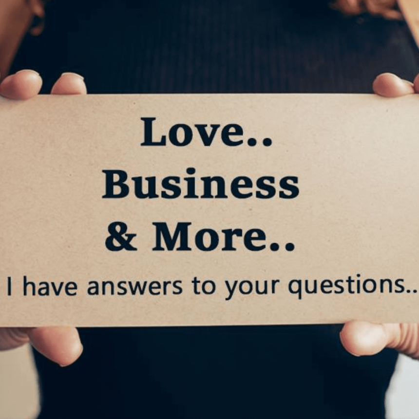 A person holding a sign that reads: Love.. Business & More.. I have answers to your questions.. The background is blurred, focusing on the sign and the persons hands.