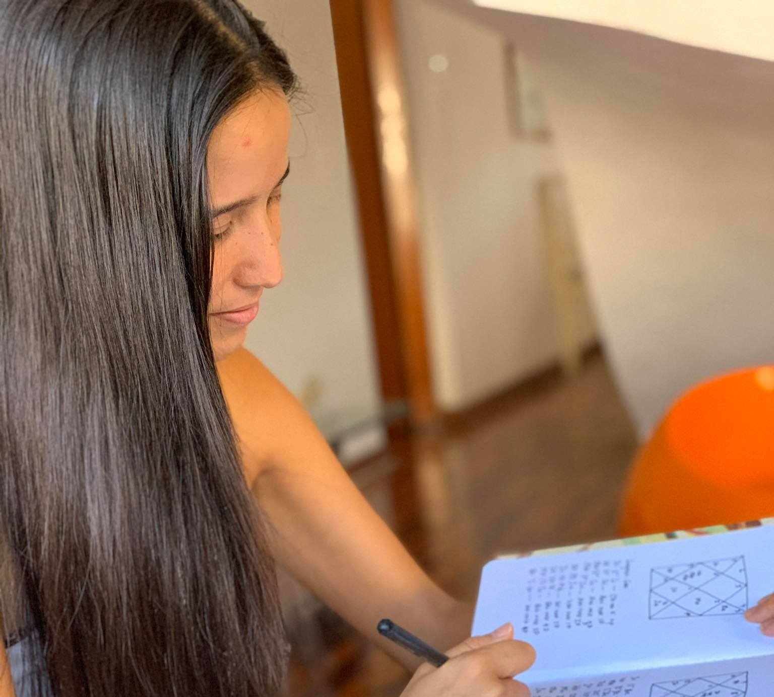 A woman taking notes on a notebook preparing a vedic astrology reading.