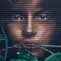 Experience the vibrant spirit of Buenos Aires with Discover Buenos Aires Street Art & Sketch—a mural of a woman’s face on a metal shutter, detailed brown eyes and lips, partly hidden by green leaves.