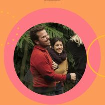 Two people laugh together outdoors, framed by vibrant pink and orange circles with Laughter As An Ally at the top. Surrounded by lush green foliage, the scene radiates a resilient, joyful vibe.