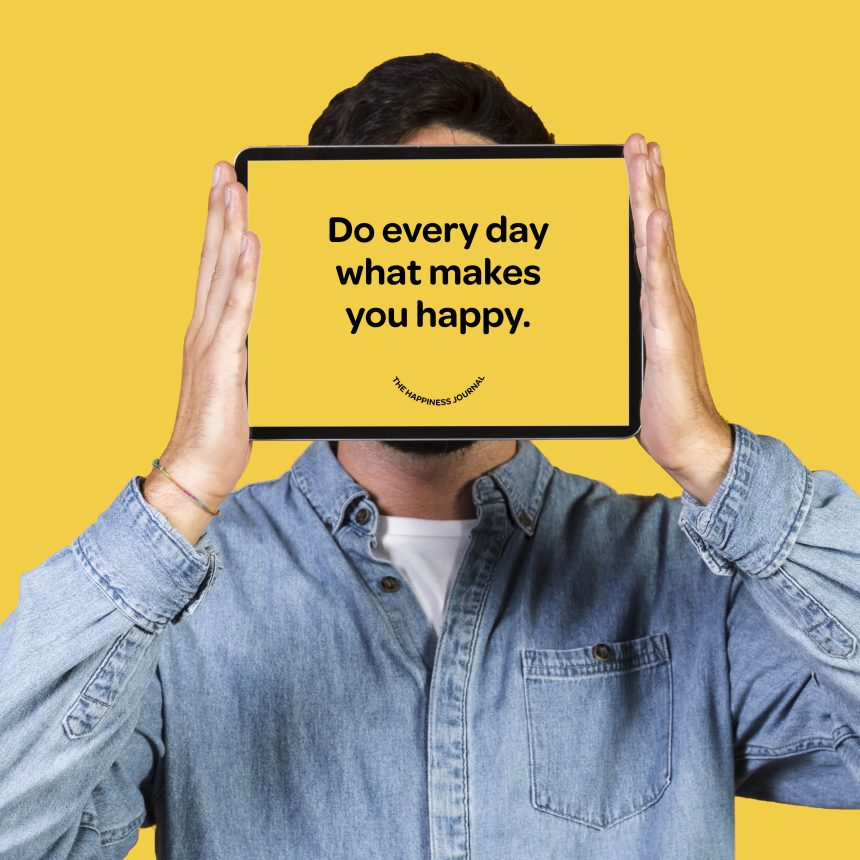 A person in a denim shirt holds a tablet in front of their face displaying “Do every day what makes you happy,” with a solid yellow background. Product: The Happiness Journal.