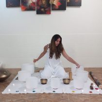 Fátima Teixeira seated with singing bowls and candles before an online sound bath.