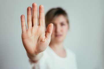 Woman holding up her hand to signal stop and assert a personal boundary