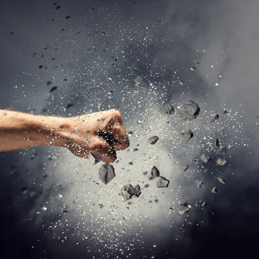 A human fist punches through a cloud of shattered black debris and dust, symbolizing the power of self-expression in Find Your Power, with particles flying outward against a dark, smoky background.