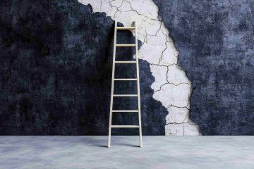 A ladder standing up against a wall that is grey and white.