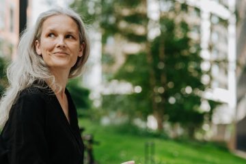 Silver-haired woman with a notebook reflecting outdoors in a city garden