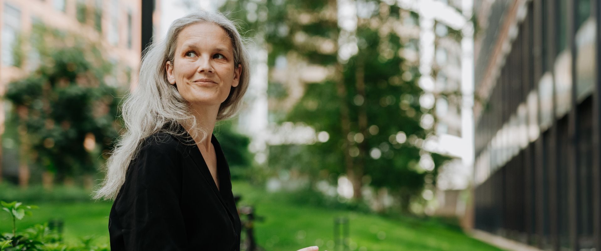 Silver-haired woman with a notebook reflecting outdoors in a city garden