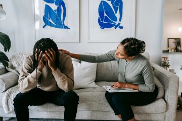Black woman sitting on coach comforting her stressed out partner