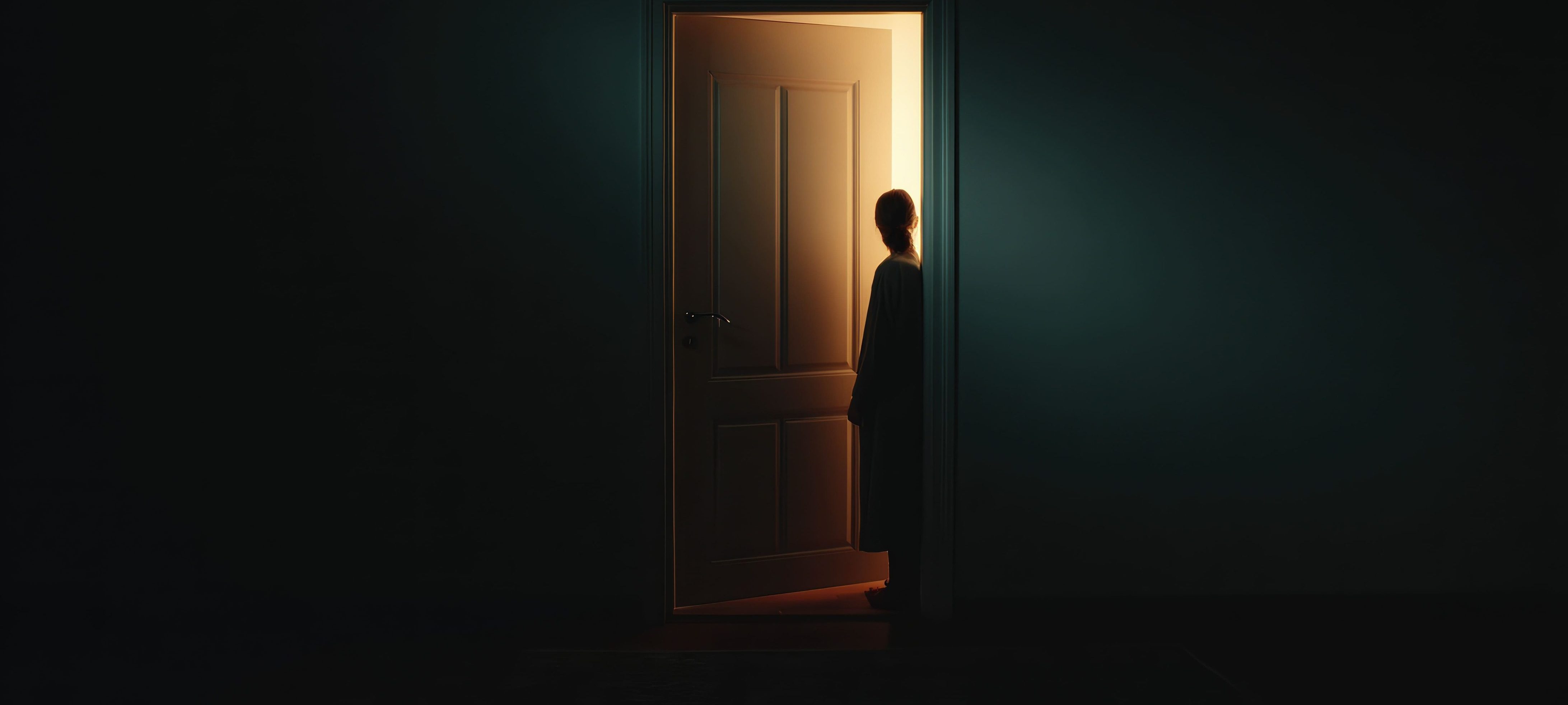 A silhouette of a person stands in a doorway, illuminated by warm light from the other side, while the surrounding room is dark and shadowy.
