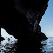 Sea kayaker paddling beside a cave in Sicily’s Aeolian Islands