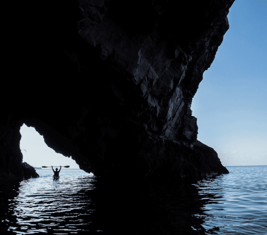 Sea kayaker paddling beside a cave in Sicily’s Aeolian Islands