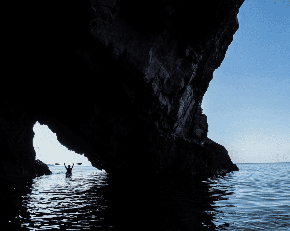 Sea kayaker paddling beside a cave in Sicily’s Aeolian Islands