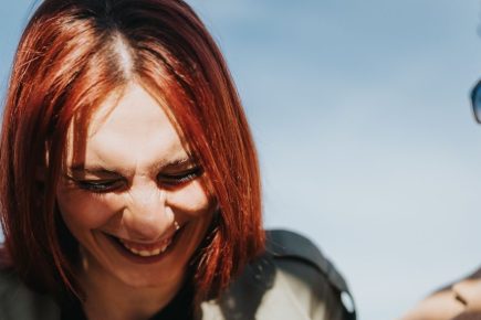 Woman laughing during an outdoor conversation with a man
