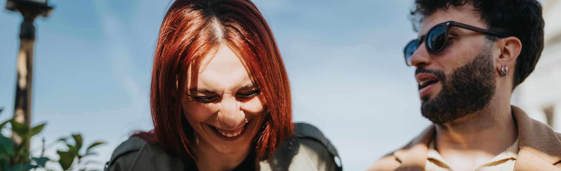 Woman laughing during an outdoor conversation with a man