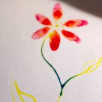 A watercolor painting of a red and pink flower with a yellow center, green stem, and two yellow leaves on white textured paper.