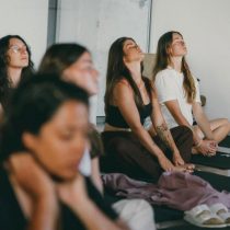 Group of women seated with their eyes closed during an indoor mindfulness practice