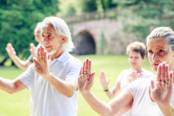 Older adults practicing tai chi outdoors, a traditional movement practice associated with cultivating chi or qi.