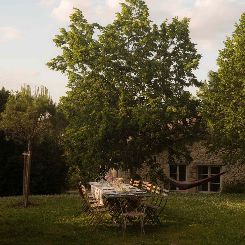 Outdoor dining area beneath trees at a Southwest France yoga retreat in Gascony