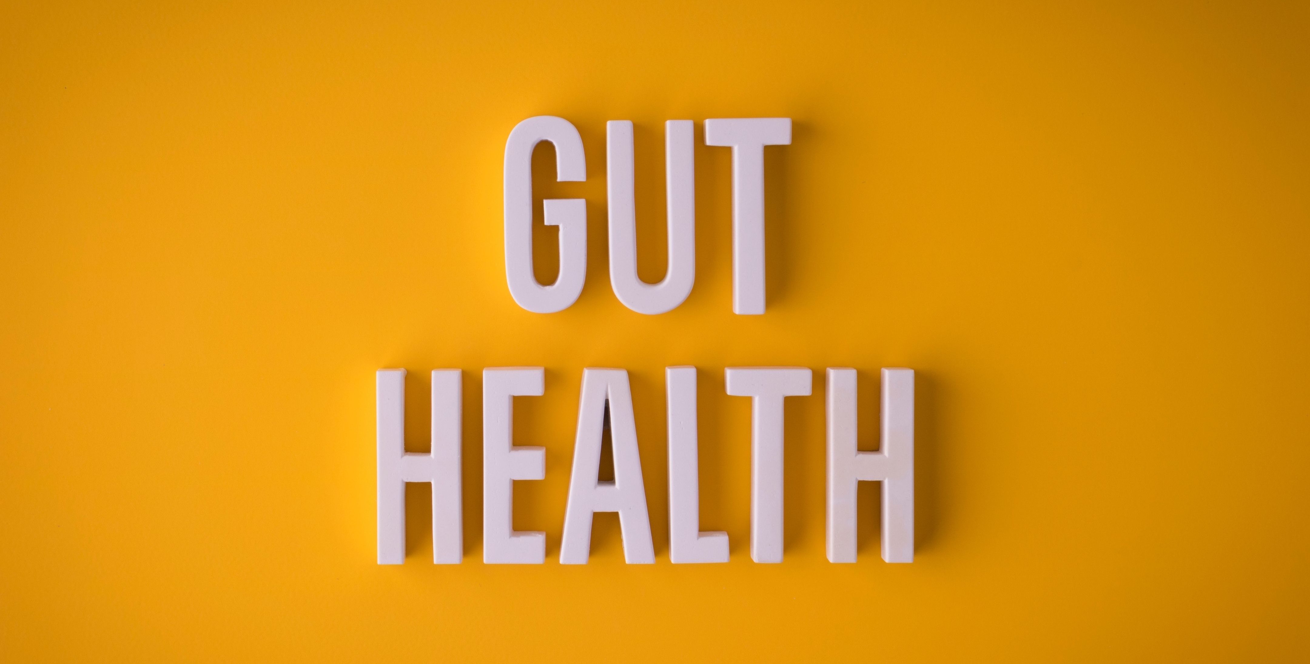 White 3D letters spelling GUT HEALTH on a bright yellow background.