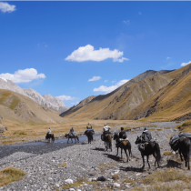 Horse riders crossing a mountain valley during a Kyrgyzstan trek