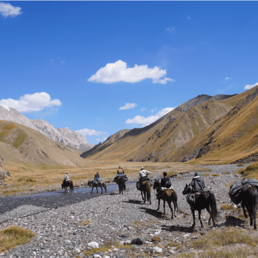 Horse riders crossing a mountain valley during a Kyrgyzstan trek