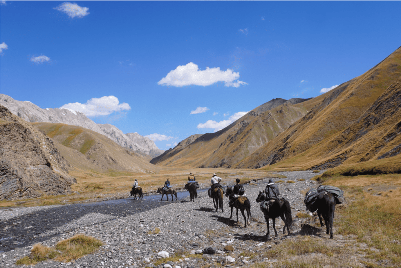 Horse riders crossing a mountain valley during a Kyrgyzstan trek