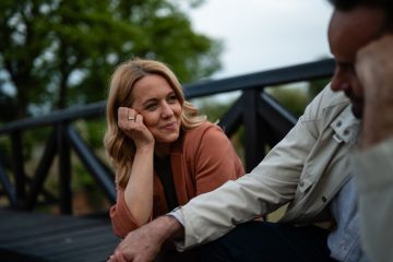 Woman smiling at a man as they sit together outdoors