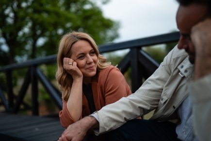 Woman smiling at a man as they sit together outdoors