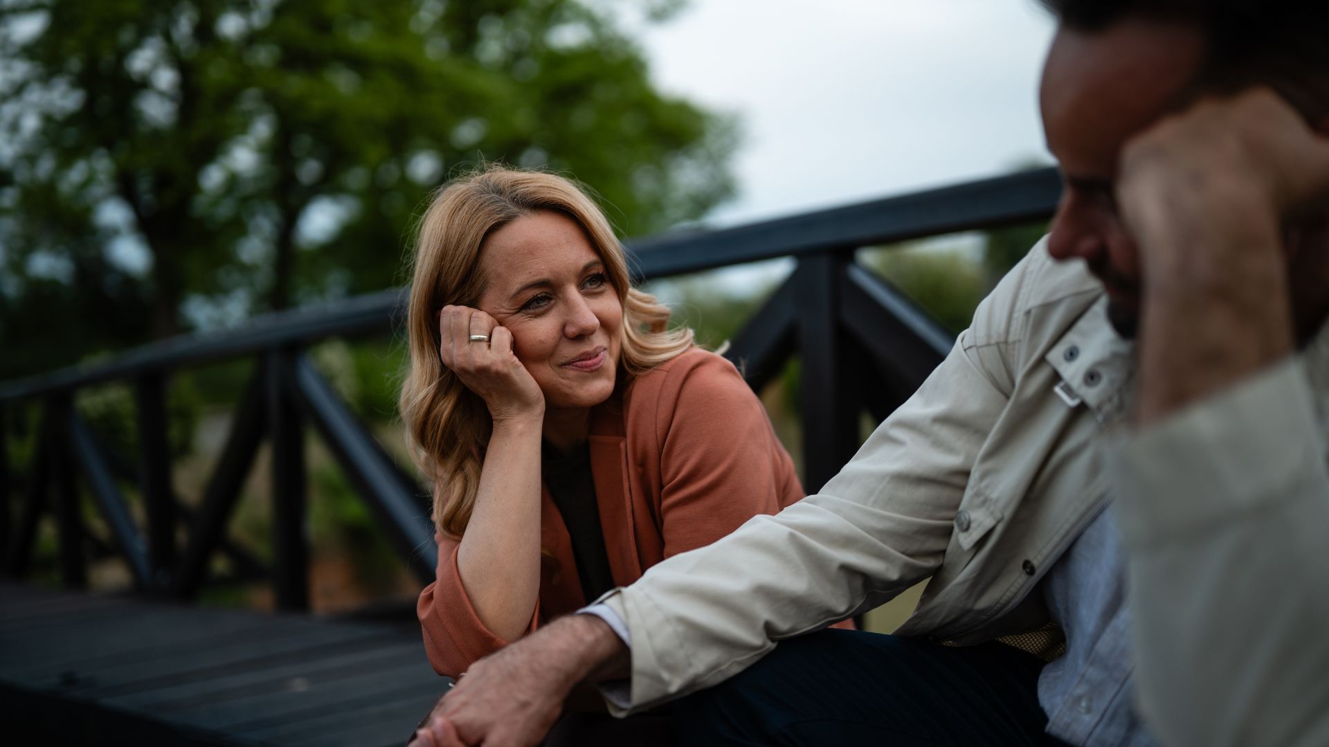 Woman smiling at a man as they sit together outdoors