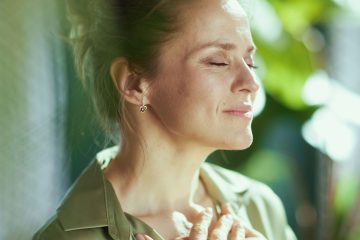 Woman practicing a grounding meditation with her hands over her heart